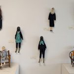 Figurines mounted on a wall of animals in clothing and memorable people in culture including Pee Wee Herman, Ruth Bader Ginsburg, and Frida Kahlo