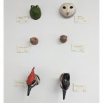 Ceramic animal heads displayed on a wall including a frog, an owl, two turtles, and two woodpeckers.
