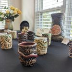 A table of ceramic cups and vases with color ridges and grooves
