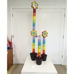Three pillar in varying lengths made of rainbow ceramic pieces with large flowers in the center or the top