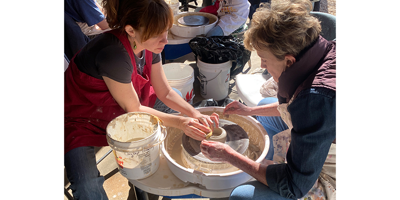 Two people molding clay on a ceramics wheel