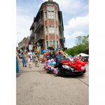 A convertable covered in colorful balloons drive through downtown Eureka Springs
