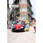 A convertable covered in colorful balloons drive through downtown Eureka Springs