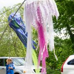 Two hand-made jellyfish are displayed from poles by parade-goers