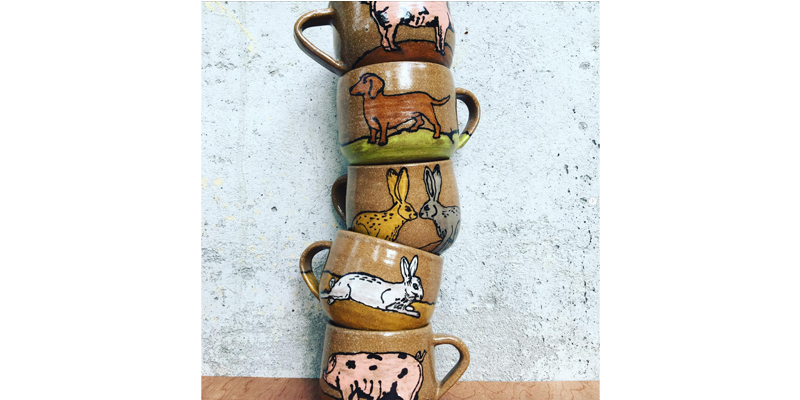 A stack of ceramic mugs with animals ordained on the sides