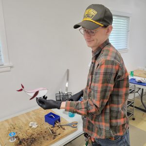 Student displaying a completed stained glass project from an ESSA Young Artist Program workshop