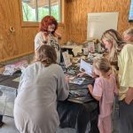 Participants gather around a table at the button-making station, creating ESSA button buttons with markers and paper.