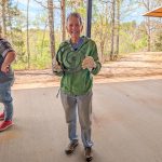 Smiling participant holding a finished a plasma-cut metal spiral artwork outdoors.