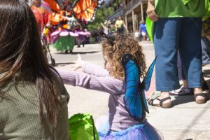 Child wearing blue butterfly wings watches the ArtRageous Parade in downtown Eureka Springs Arkansas
