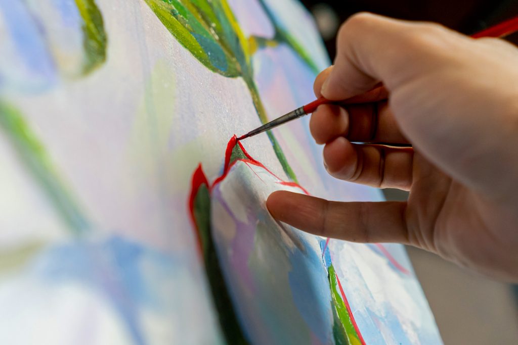 Artist applying paint to a canvas with a fine brush
