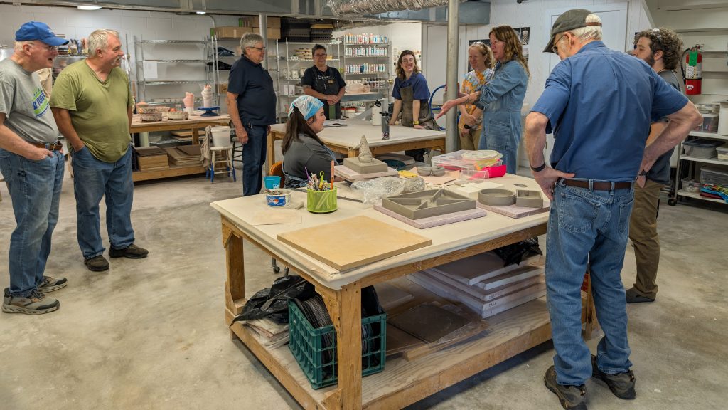 Ceramics residents Kaitlyn Cirielli and Erin Harris talk with a group of woodworking residents in the ESSA Ceramics Studio.