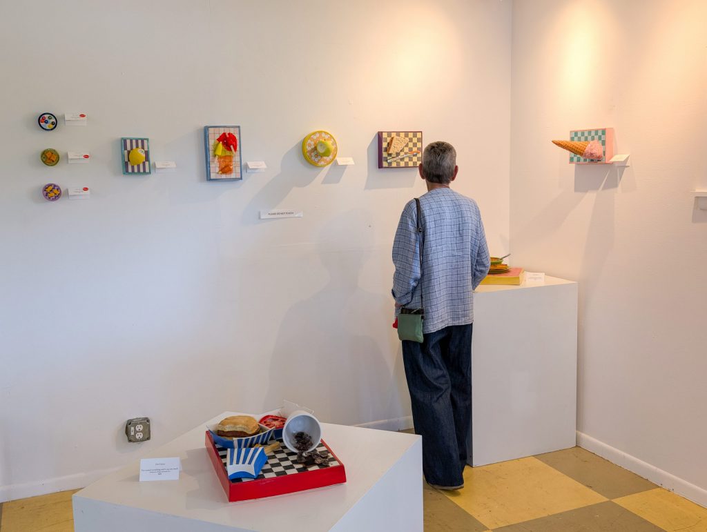 Guest views ceramic food sculptures by Erin Harris displayed on the gallery wall at ESSA.