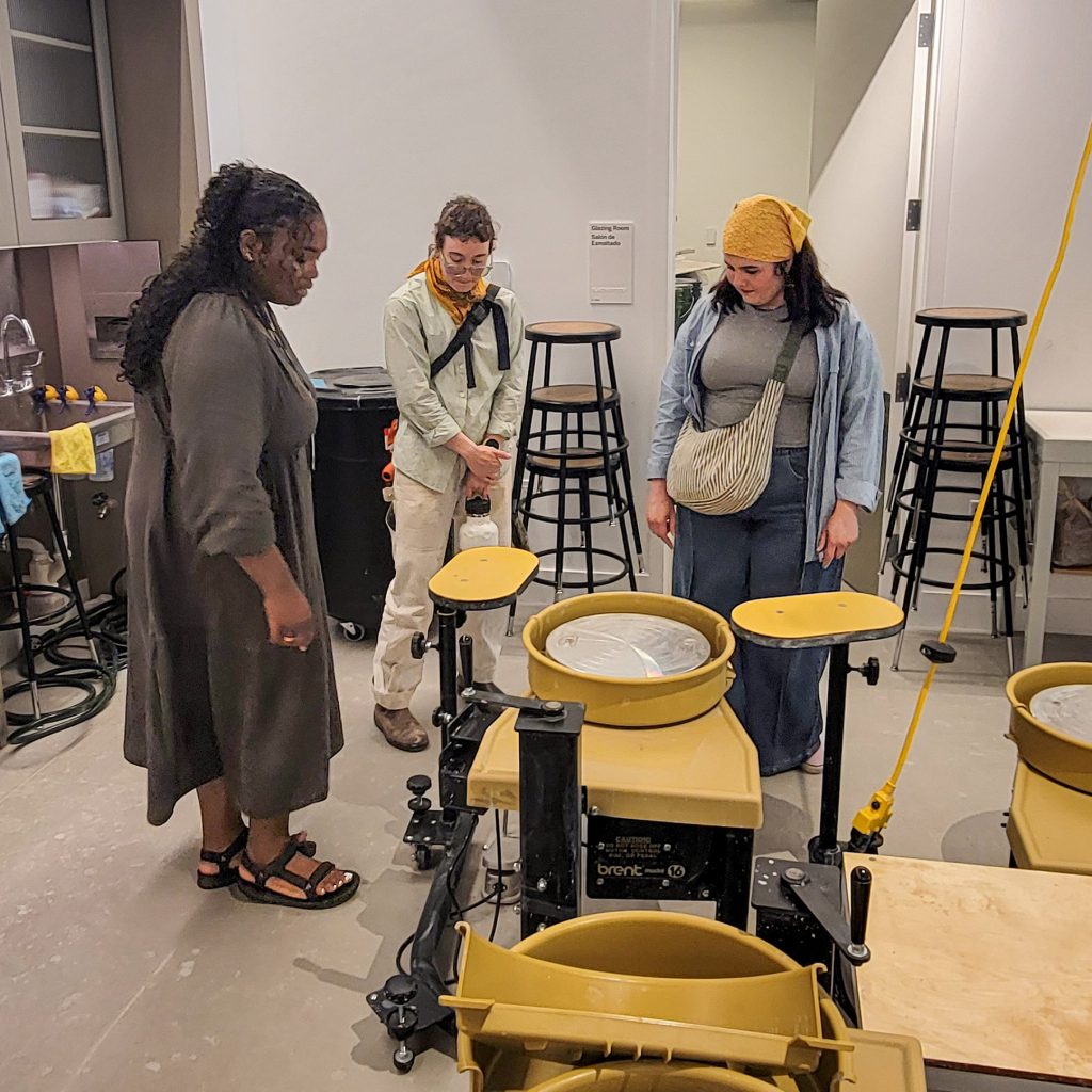 Museum staff member Carlita shows Kaitlyn Cirielli and Erin Harris an accessible pottery wheel in the Hub at Crystal Bridges.