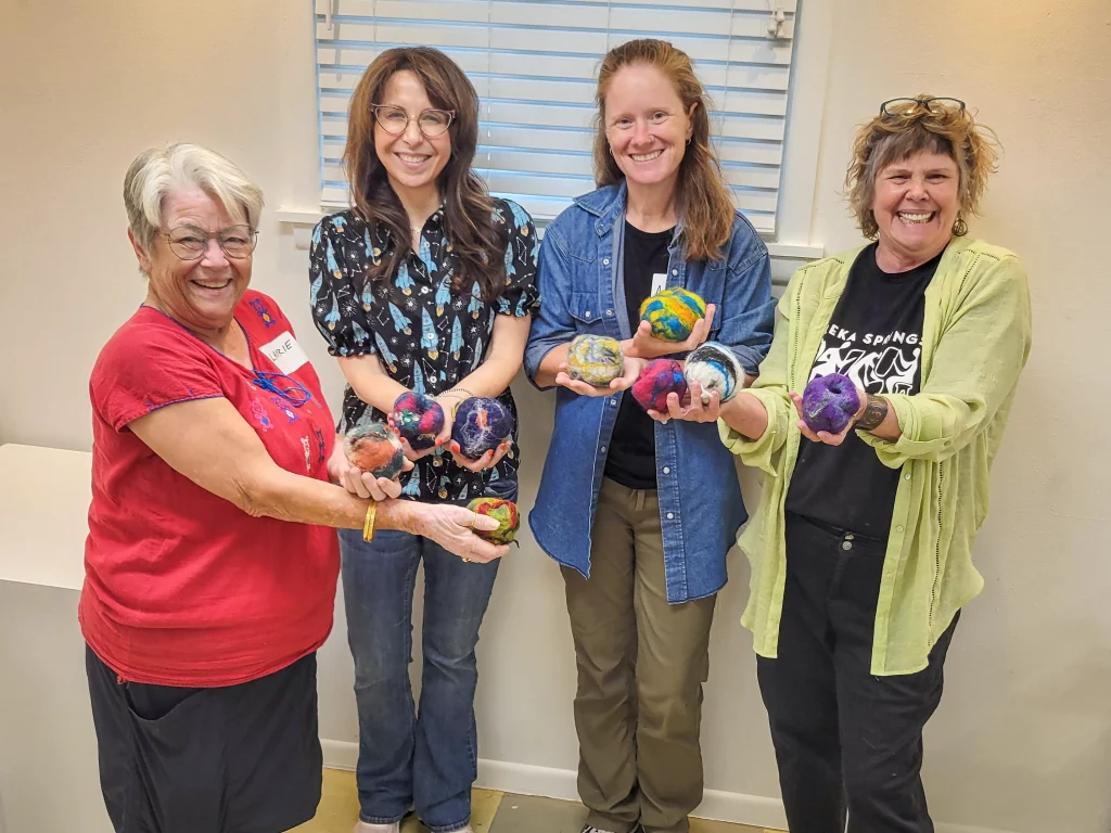 ESSA workshop participants holding colorful felted artwork